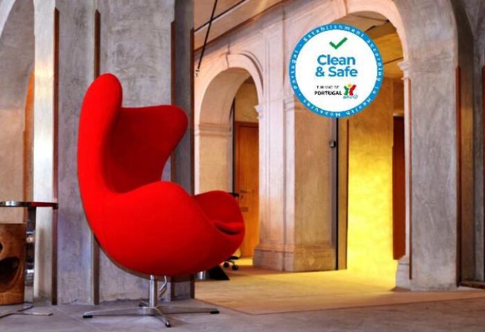 Interior of Browns Downtown Hotel, a gay-friendly hotel. Red Egg chair and Clean & Safe badge. Arched doorways and modern design.