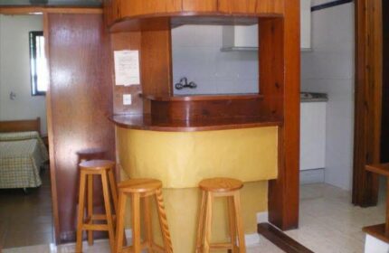 Interior view of Bungalows Tenesoya, a gay-friendly hotel. Bar with stools, kitchenette, and bedroom visible. Gay men travel.