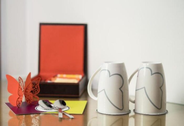 Butterfly art, spoons, and tea box at LKF Boutique Hotel Central, a gay-friendly hotel. Mugs with leaf design. Gay travel lodging.