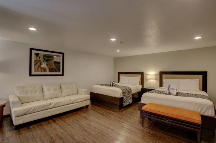 CCBC Resort Hotel room. Gay-friendly hotel with two beds, a white couch, and a bench. A gay men's resort for travel and relaxation.