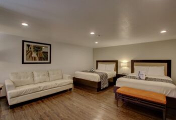 CCBC Resort Hotel room. Gay-friendly hotel with two beds, a white couch, and a bench. A gay men's resort for travel and relaxation.