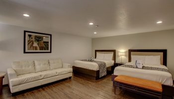 CCBC Resort Hotel room. Gay-friendly hotel with two beds, a white couch, and a bench. A gay men's resort for travel and relaxation.