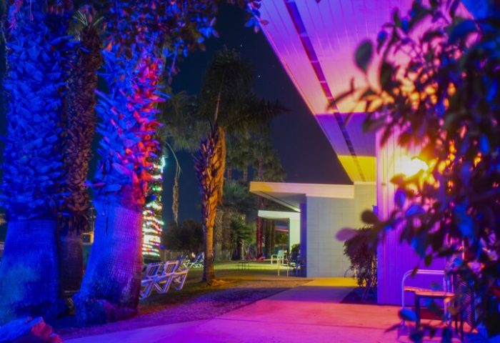 CCBC Resort Hotel, a gay men's resort. Night view with palm trees illuminated with blue and red lights, creating a vibrant, gay-friendly atmosphere.