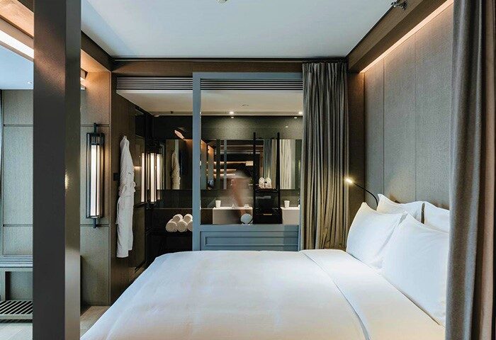 CHAO Sanlitun Beijing gay-friendly hotel room. View of the bed, bathroom with mirrors, and modern design. Best gay hotels in Beijing.