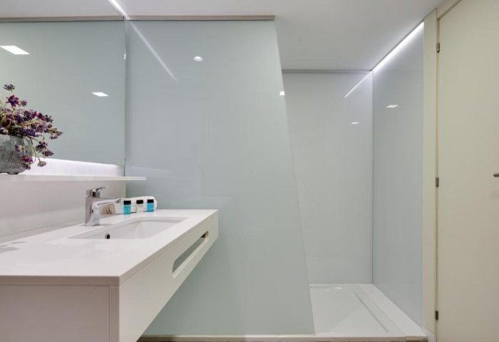 Hotel Calipolis bathroom. Modern, bright interior with white sink, shower, and frosted glass. Gay-friendly hotel design for travel advice.