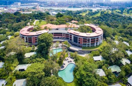 Capella Singapore Hotel aerial view. Gay-friendly hotel with pools, surrounded by lush greenery. Luxury travel destination.