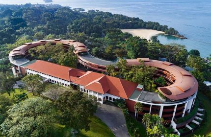 Aerial view of Capella Singapore Hotel, a gay-friendly resort with unique architecture, nestled in lush greenery near the beach. Perfect for gay travel.