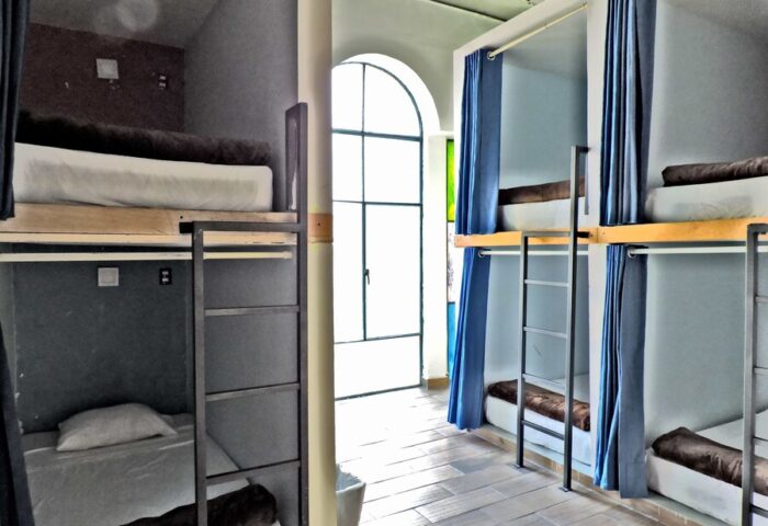 Capsule Hostel interior. Bunk beds with curtains, ladders, and individual sleeping pods. Gay-friendly hotel for budget travelers.