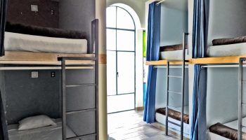 Capsule Hostel interior. Bunk beds with curtains, ladders, and individual sleeping pods. Gay-friendly hotel for budget travelers.