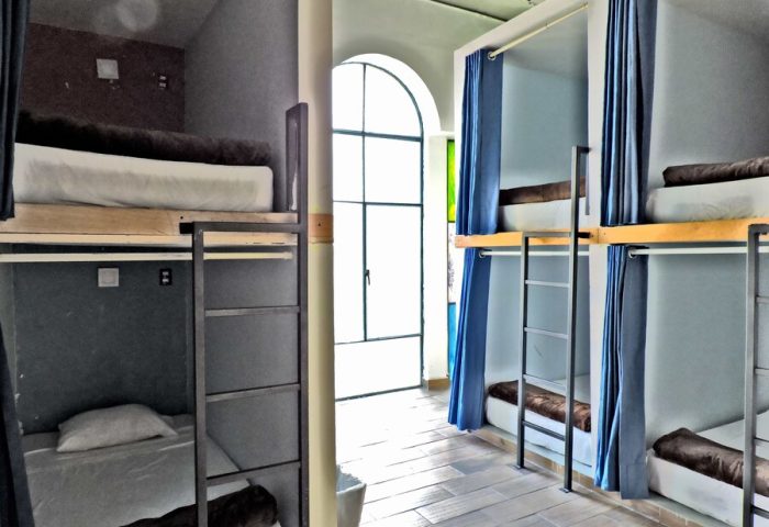 Capsule Hostel interior. Bunk beds with curtains, ladders, and individual sleeping pods. Gay-friendly hotel for budget travelers.