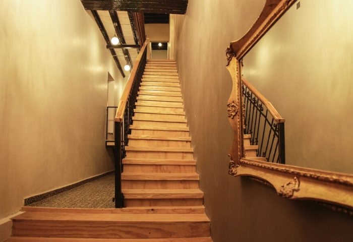 Stairway at Gay-Friendly Capsule Hostel. Interior view of the Capsule Hostel, featuring wooden stairs and a decorative mirror. Travel advice.