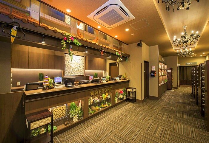 Capsule Hotel Anshin Oyado Premier Tokyo Shinjuku Station lobby. Gay-friendly hotel with reception desk, parrots, plants, and chandeliers.