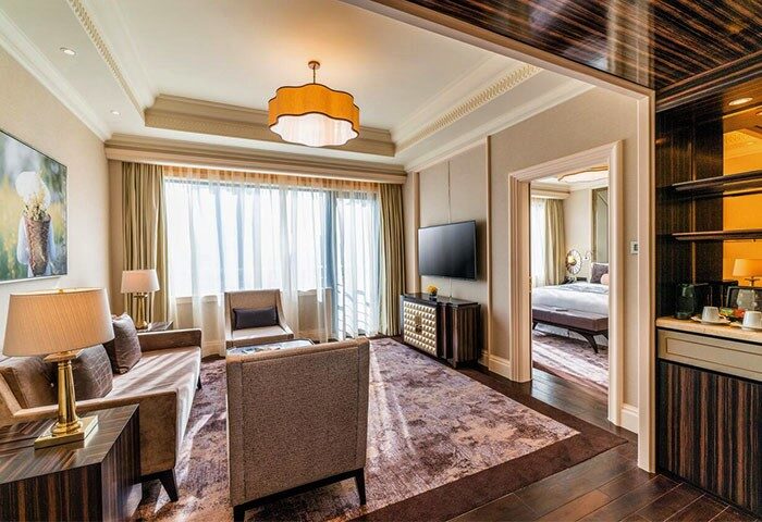 Caravelle Saigon Hotel suite. Gay-friendly hotel room with living area, TV, seating, and view into bedroom. Upscale Saigon travel.