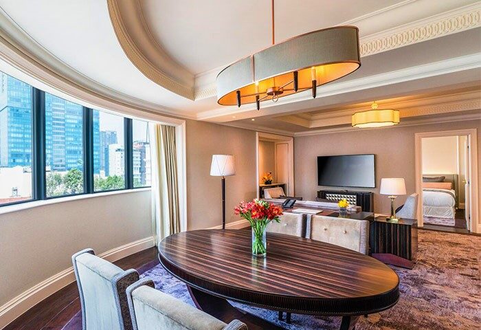 Caravelle Saigon Hotel's suite. Gay-friendly hotel room with city view, desk, TV, and bedroom access. Luxury travel in Ho Chi Minh City.