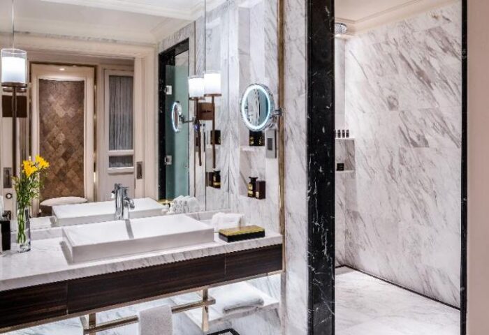 Bathroom at Gay-Friendly Caravelle Saigon Hotel: Double sinks, marble walls, and a walk-in shower. Luxury hotel for gay travelers in Saigon.