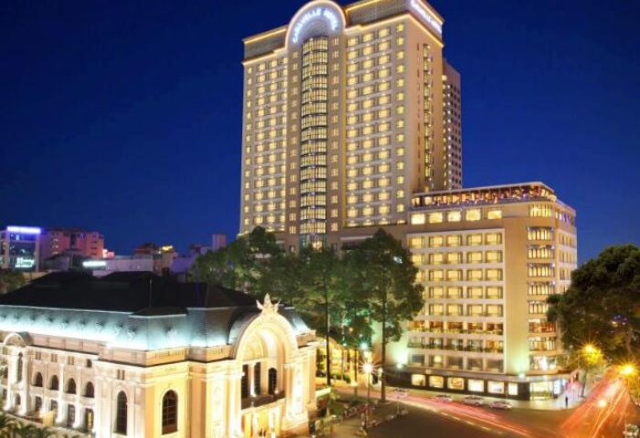 Night view of Caravelle Saigon Hotel, a gay-friendly hotel in Ho Chi Minh City, Vietnam. The hotel is brightly lit against the dark sky.