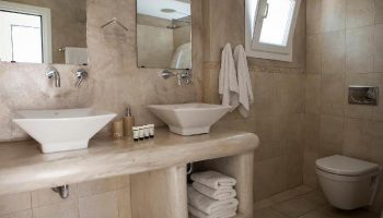 Bathroom at Carbonaki Hotel, a gay-friendly hotel. Double sinks, marble countertop, and neutral tones create a relaxing atmosphere. #Mykonos #GayTravel