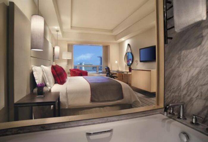 Carlton Hotel Singapore gay-friendly room reflected in bathroom mirror. Luxurious bed, city view. A great choice for gay travelers.