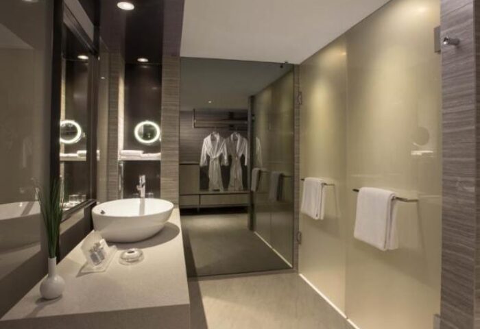 Carlton Hotel Singapore bathroom. Modern design with sink, shower, and bathrobes. Gay-friendly hotel for gay men's travel advice.