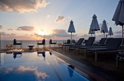 Carlton Tel Aviv Hotel luxury pool at sunset. Gay-friendly hotel on the beach with lounge chairs and ocean view. Perfect for gay travel.