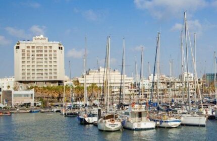 Carlton Tel Aviv Hotel view from the marina. Luxury gay-friendly hotel on the beach, with yachts and blue sky. A top gay travel destination.