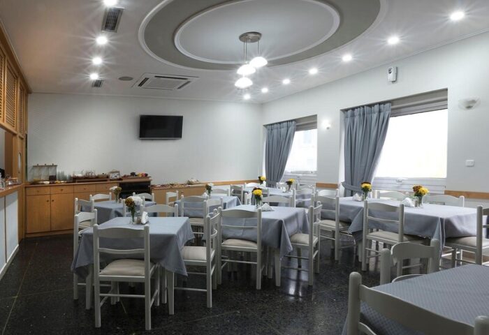 Dining area at Carolina Hotel, a gay-friendly hotel. Tables with gray tablecloths and white chairs are arranged in a well-lit room.