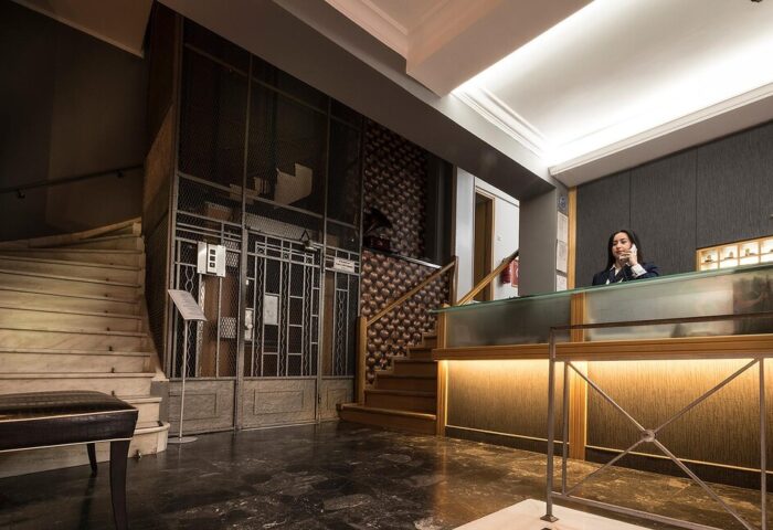 Carolina Hotel's reception area. Woman at the front desk of this gay-friendly hotel. Stairs and elevator visible.