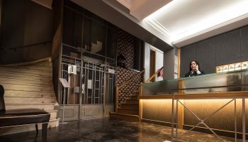 Carolina Hotel's reception area. Woman at the front desk of this gay-friendly hotel. Stairs and elevator visible.