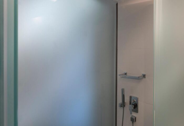 Shower at Carolina Hotel, a gay-friendly hotel. Features include frosted glass, a rainfall shower head, and handheld sprayer.