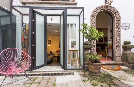 Casa Comtesse, a gay-friendly hotel. Exterior view with an open glass doorway, stone archway, and pink chair. Boutique hotel travel advice.