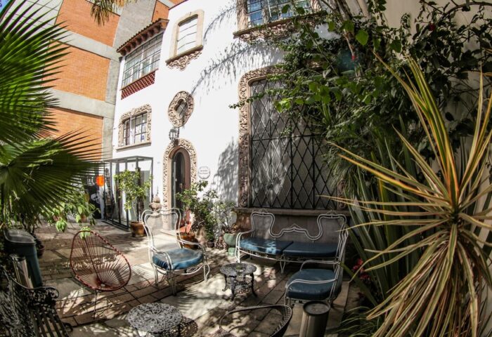 Casa Comtesse, a gay-friendly hotel: Courtyard with ornate white building, wrought iron furniture, and lush greenery. Ideal for gay travel.