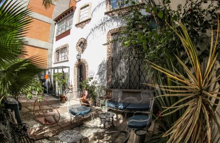Casa Comtesse, a gay-friendly hotel: Courtyard with ornate white building, wrought iron furniture, and lush greenery. Ideal for gay travel.