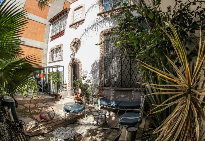 Casa Comtesse, a gay-friendly hotel: Courtyard with ornate white building, wrought iron furniture, and lush greenery. Ideal for gay travel.