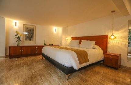 Casa Comtesse gay-friendly hotel room. Bedroom with a queen bed, wooden furniture, marble floors, and warm lighting. Ideal gay travel stay.