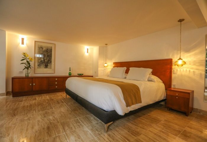 Casa Comtesse gay-friendly hotel room. Bedroom with a queen bed, wooden furniture, marble floors, and warm lighting. Ideal gay travel stay.