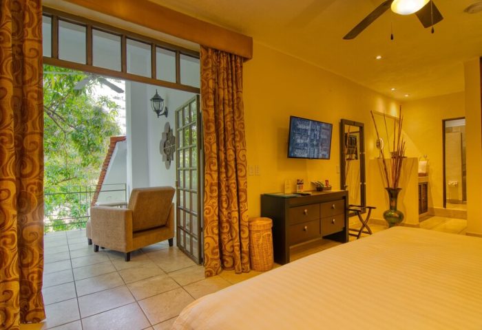 Casa Cupula gay-friendly hotel room with balcony. Interior view of bedroom with TV, dresser, and open balcony at a gay resort in Puerto Vallarta.