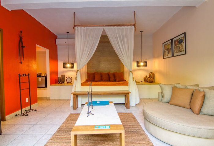 Casa Cupula, gay-friendly hotel room featuring a four-poster bed with white curtains, a round sofa, and a coffee table. Luxury gay travel.