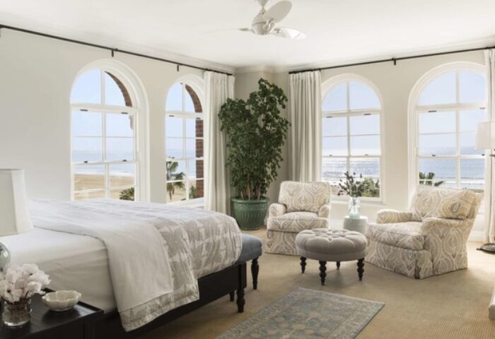 Casa Del Mar gay-friendly hotel room. Beach view from arched windows. Bed, chairs, ottoman, and plant. Upscale gay travel lodging.