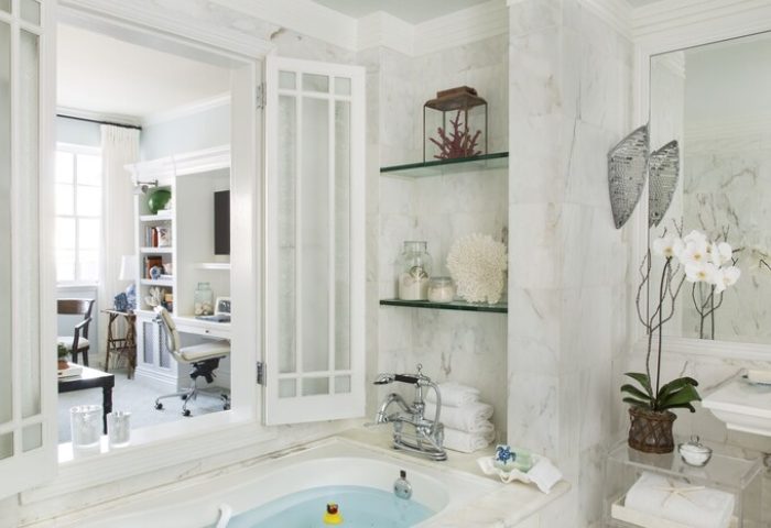 Casa Del Mar gay-friendly hotel: Marble bathroom with a tub, open doors to an office. Shelves display coral and decorative items.