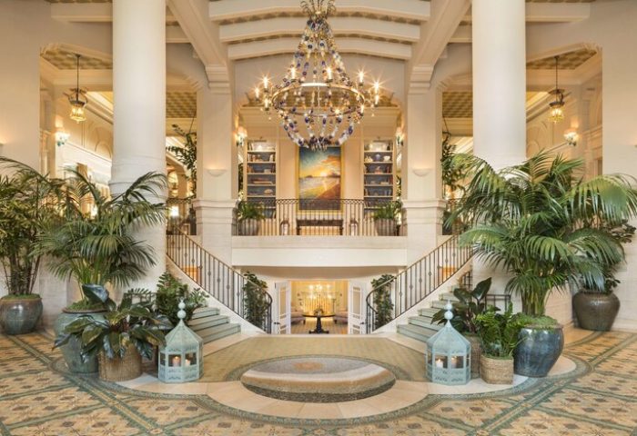 Casa Del Mar's grand lobby. This gay-friendly hotel features a chandelier, staircase, plants, and a painting. Luxury travel for gay men.
