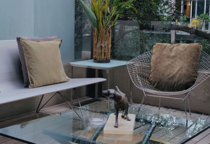 Casa Mannach, gay-friendly hotel: Outdoor lounge area with glass table, seating, and garden view. A relaxing space for gay travelers.