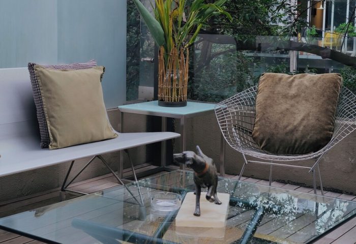 Casa Mannach, gay-friendly hotel: Outdoor lounge area with glass table, seating, and garden view. A relaxing space for gay travelers.