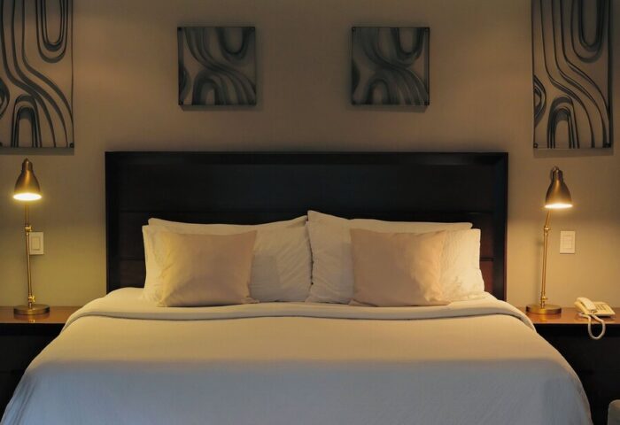 Casa Mannach gay-friendly hotel room. King bed with white linens, bedside lamps, and modern art. Gay travel lodging.