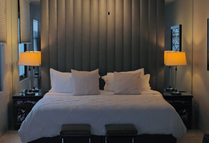 Casa Mannach's gay-friendly hotel room: King bed with padded headboard, ceiling fan, bedside tables with lamps, and two stools at the bed's foot.