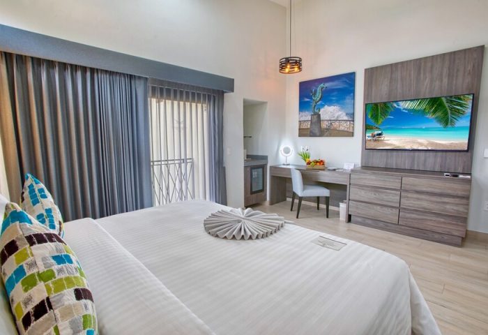 Casa Nicole Boutique Hotel room. Gay-friendly hotel featuring a bed, desk, TV, and balcony. Ideal for gay men's travel, offering comfort.