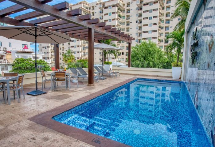 Casa Nicole Boutique Hotel's pool area. Gay-friendly hotel with rooftop pool, lounge chairs, umbrellas, and city views. Relaxing travel.