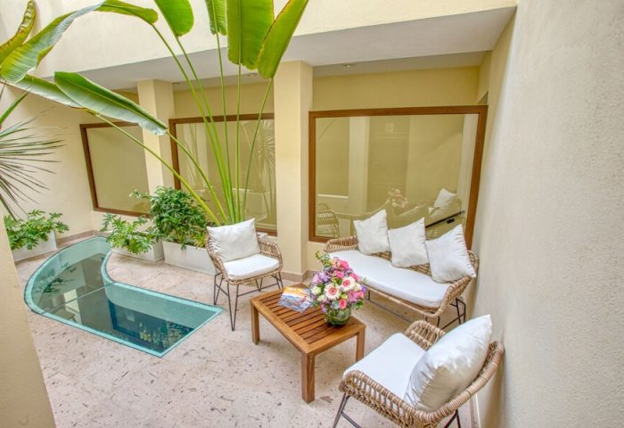 Casa Nicole Boutique Hotel gay-friendly space. Outdoor seating area with sofa, chairs, table, flowers, and plants. Relaxing hotel courtyard.