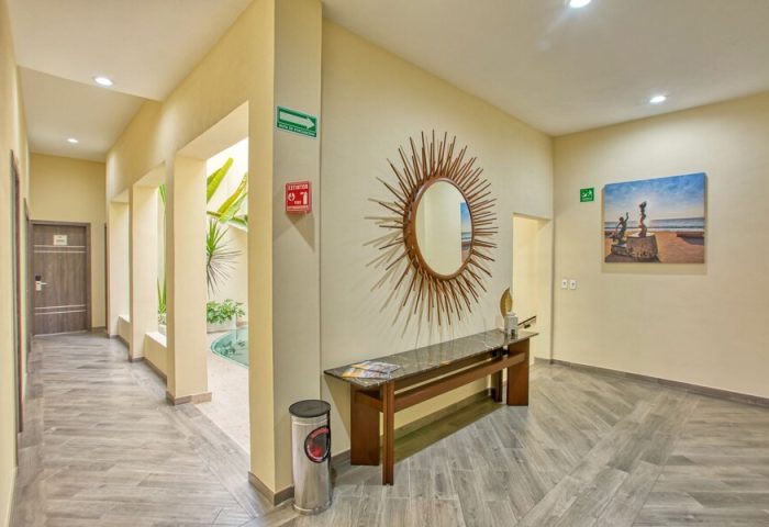 Casa Nicole Boutique Hotel hallway. Gay-friendly hotel with a sunburst mirror, bench, art, and an open-air courtyard. Modern design.