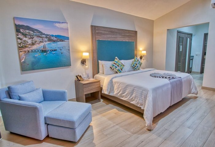 Casa Nicole Boutique Hotel gay-friendly room. Queen bed, blue accents, beach art. Modern design, comfy chair. Ideal for gay travelers.