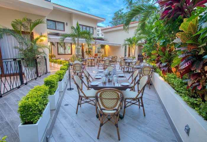 Casa Nicole Boutique Hotel's outdoor dining area. This gay-friendly hotel offers a relaxing atmosphere with lush greenery and elegant tables.